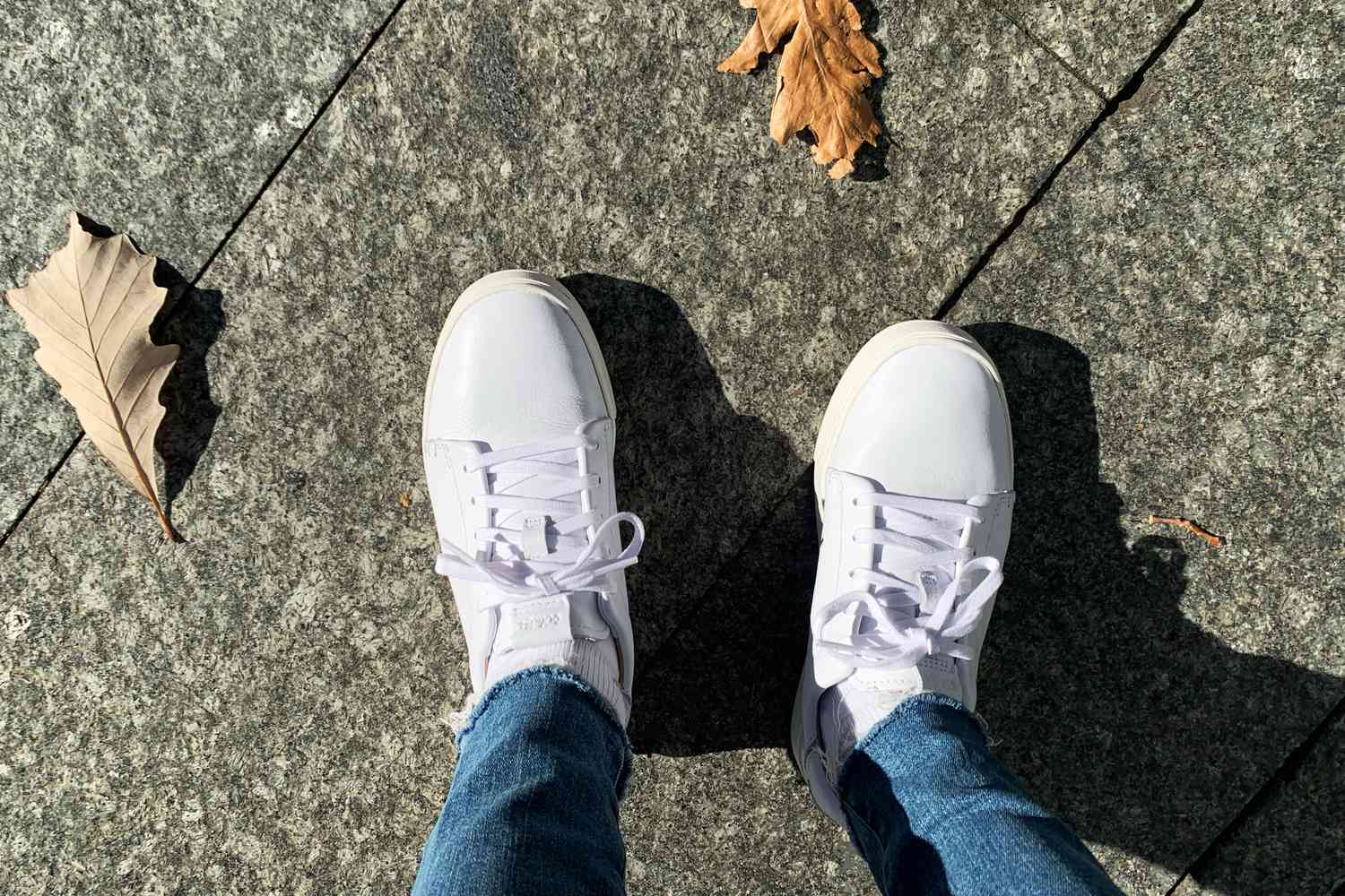 Person wearing the Olukai Pehuea Lī ‘Ili Women’s Leather Sneakers outdoors