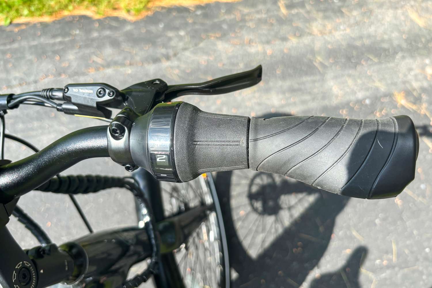 A Priority e-bike handlebar with a grip and gear shift visible, taken outdoors on a paved surface