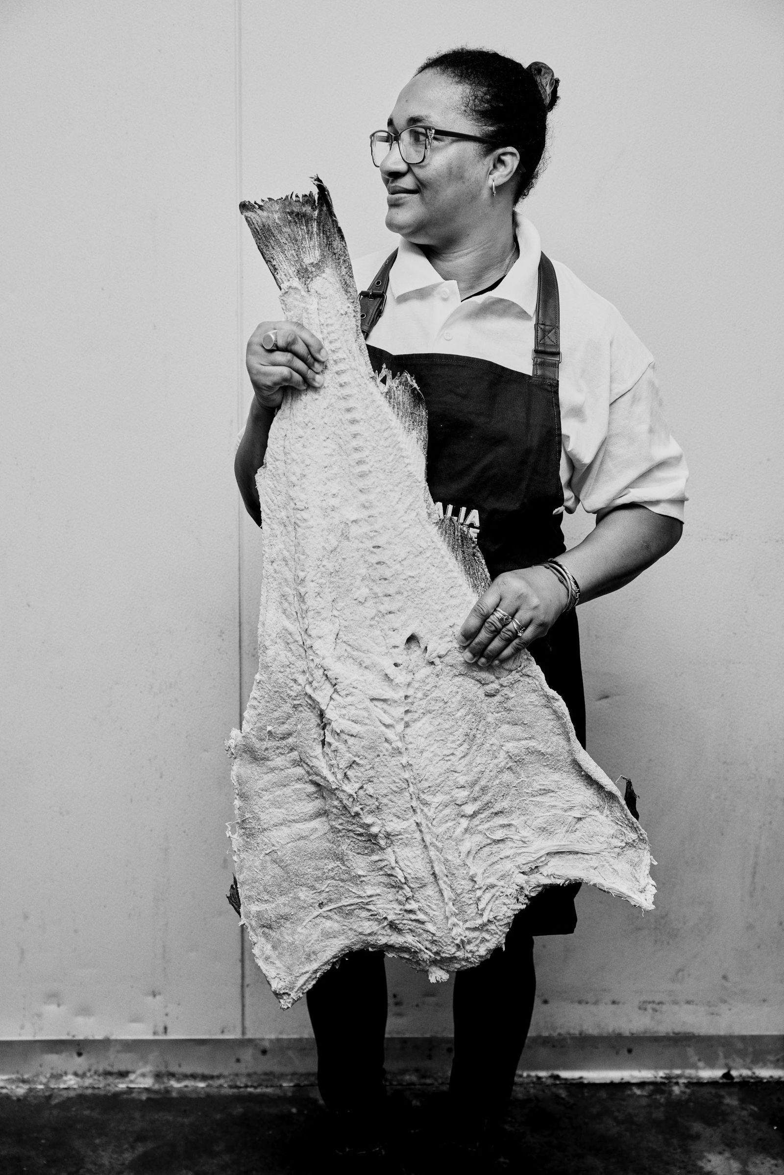 Black and white photo of a person holding a large dried cod filet