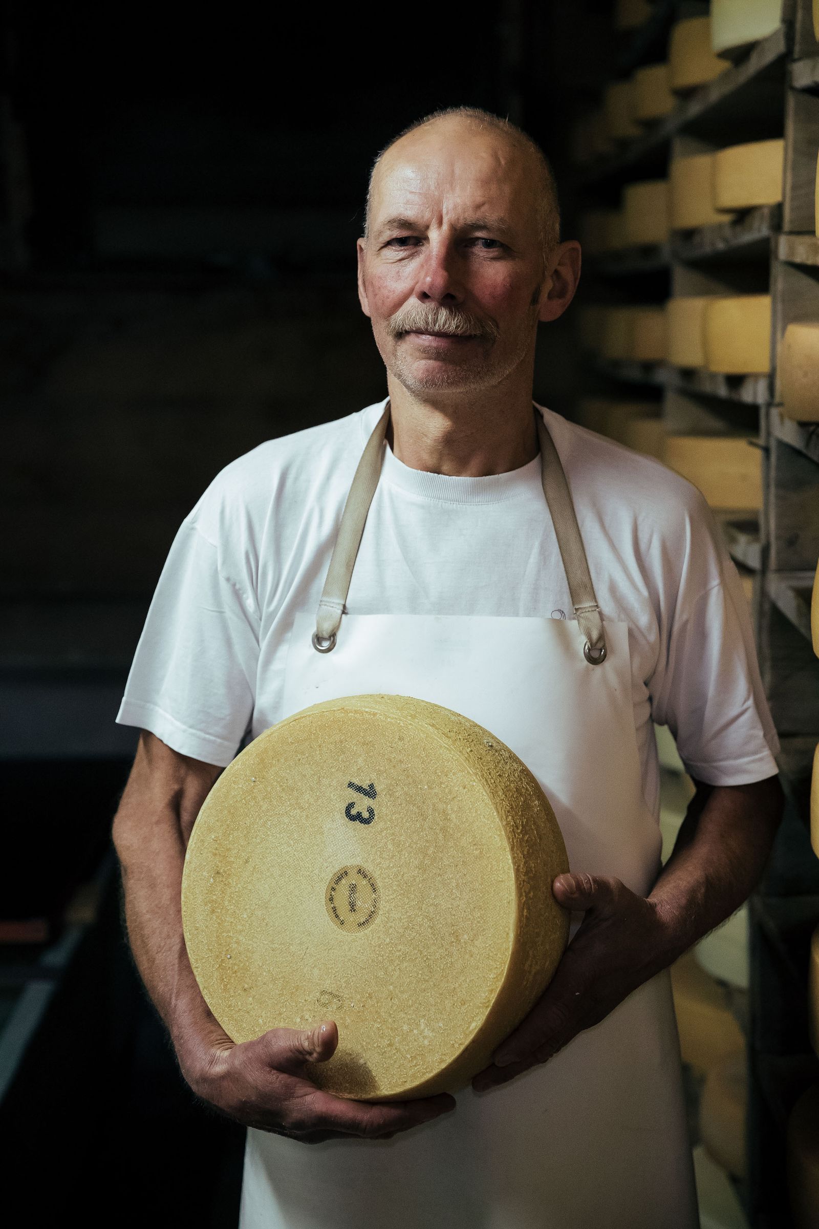 A person holding a large wheel of cheese