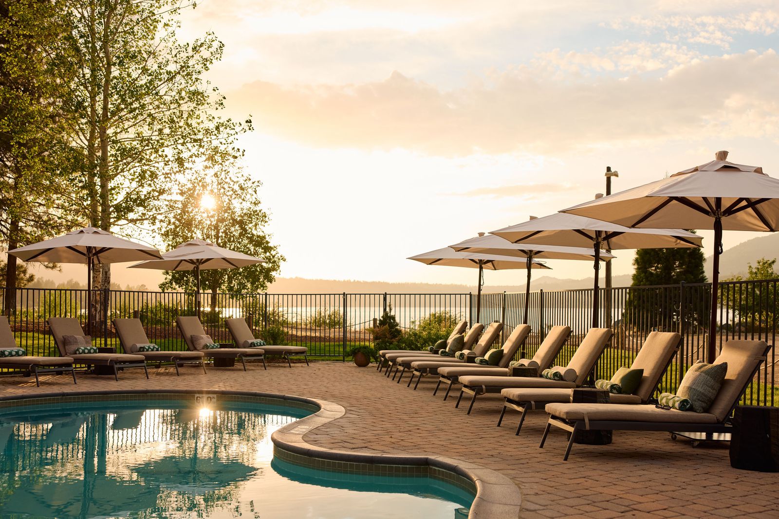 Outdoor pool lounge chairs and umbrellas at sunset