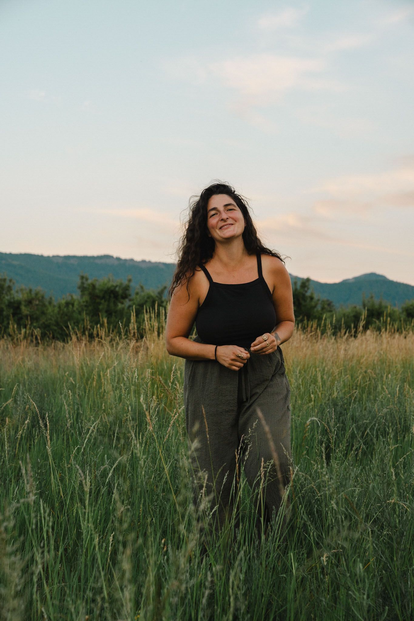 Image may contain Face Head Person Photography Portrait Grass Plant Clothing Pants Happy Smile Blouse and Field