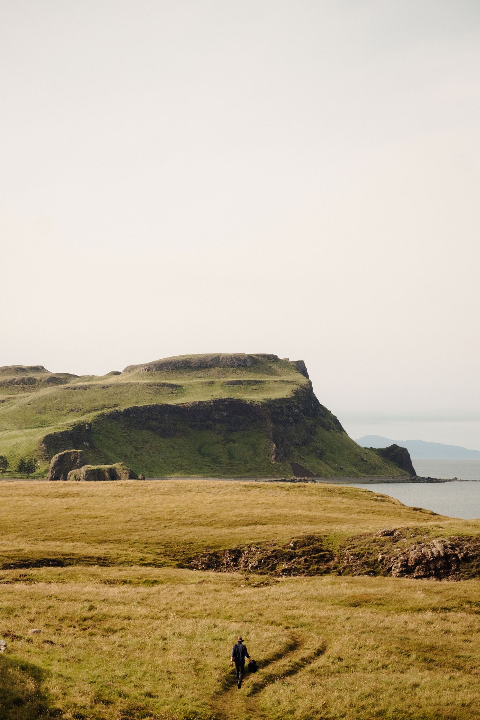 Image may contain Land Nature Outdoors Landscape Scenery Grass Plant Rock Field Grassland Sea Water and Person