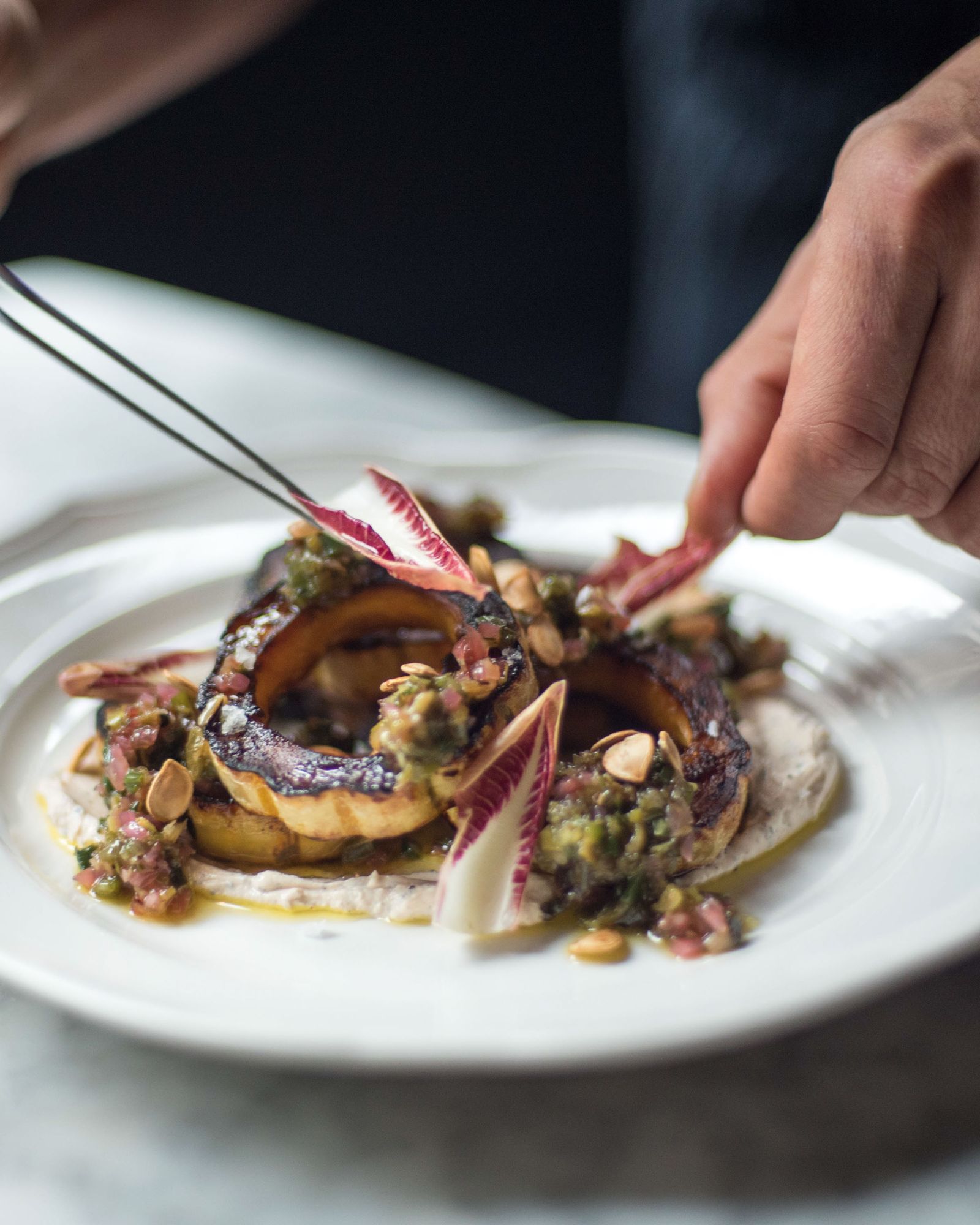 Closeup of a chef plating a dish at  La Compagnie Centre Street
